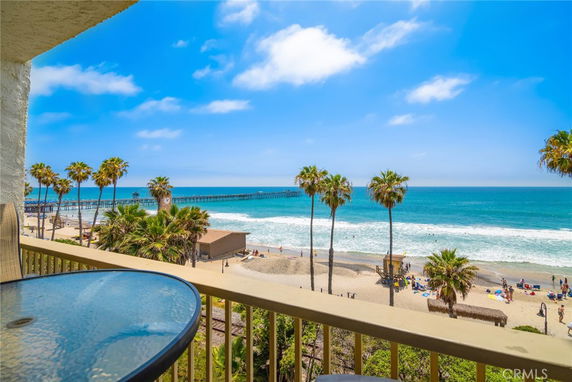 Panoramic view of a beach with palm trees and ocean from a balcony.