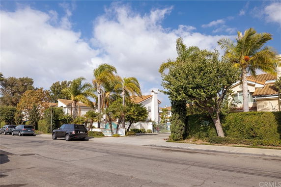Front view of a residential building with palm trees and a gated entrance.