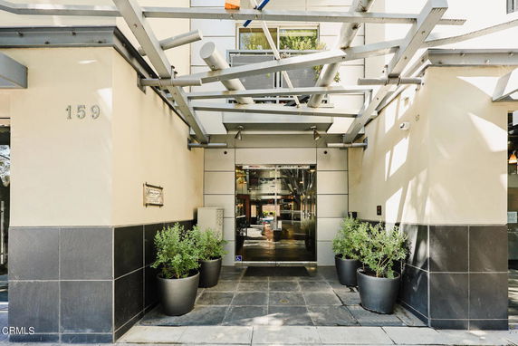 Front view of a building with a modern entrance and decorative plants.
