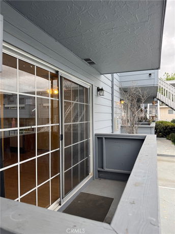 View from a building's balcony showing sliding glass doors and adjacent structures.