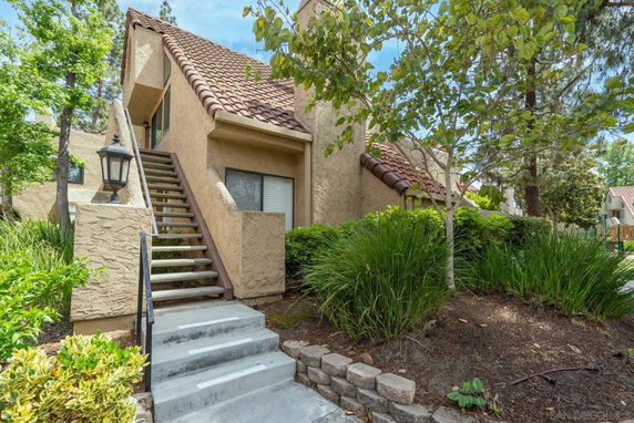 Front view of a multi-story house with an external staircase and textured walls.