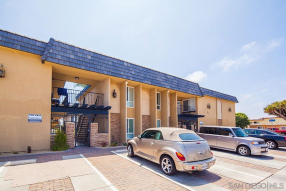 Front view of a two-story apartment building with parking area in front.