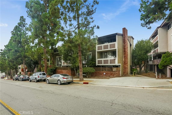 Front view of a multi-story residential building with balconies and brick accents.