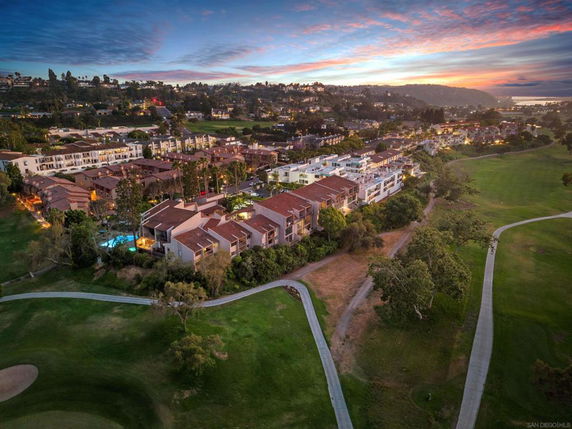 Aerial panoramic view of a residential area at dusk with surrounding landscape.