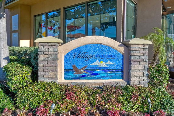 Front view of building with decorative sign, featuring large windows and landscaping.