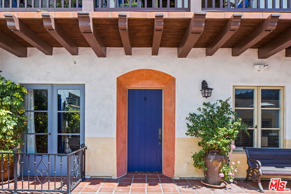Front view of a house with a blue door and decorative plants.