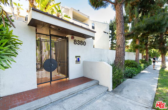 Front view of a building entrance with a gated entry and street number 8380.