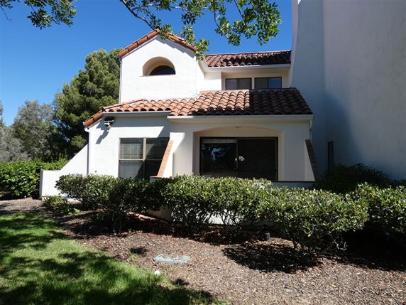 Front view of a two-story house with tiled roof and large windows.