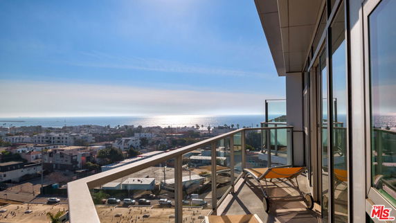 Panoramic view from a high-rise building balcony overlooking the ocean and cityscape.