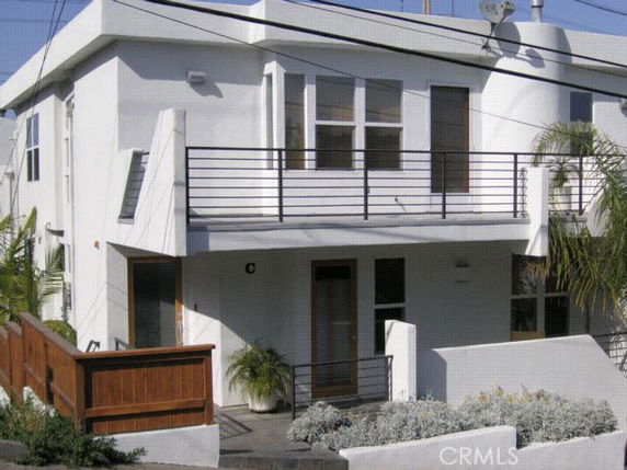Front view of a two-story modern house with a balcony and flat roof.