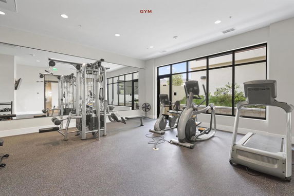 Interior view of a gym with exercise machines and large windows.