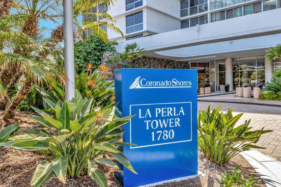 Front view of a building with a sign reading 'La Perla Tower 1780' and a landscaped entrance.
