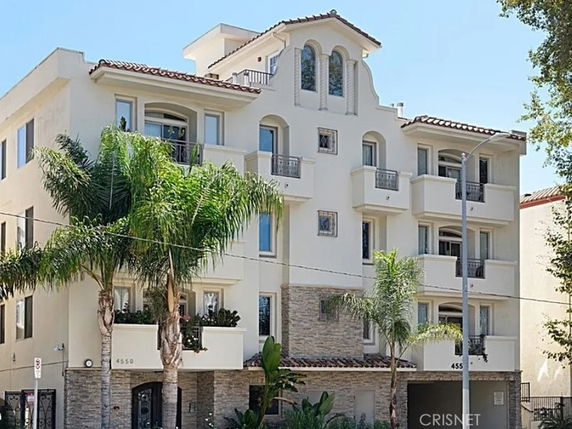 Front view of a multi-story residential building with balconies and a decorative façade.