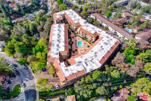 Aerial view of a large residential complex with a central swimming pool and surrounding greenery.