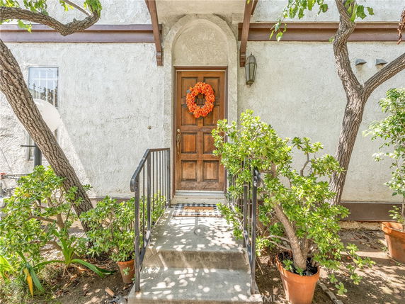 Front view of a building entrance with a wooden door and steps, adorned with a wreath.