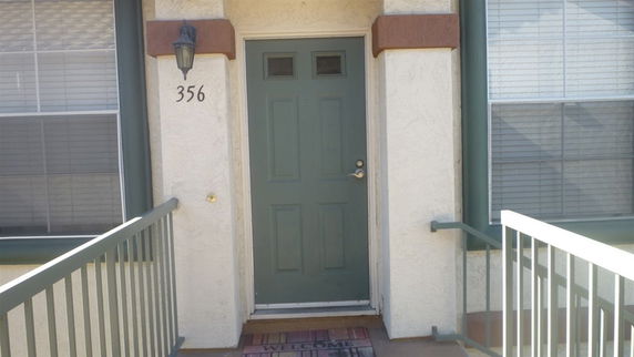 Entrance of a house with a green door and a welcome mat.