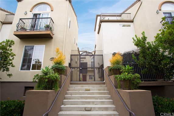 Front view of a multi-story building with balconies and gated entrance.