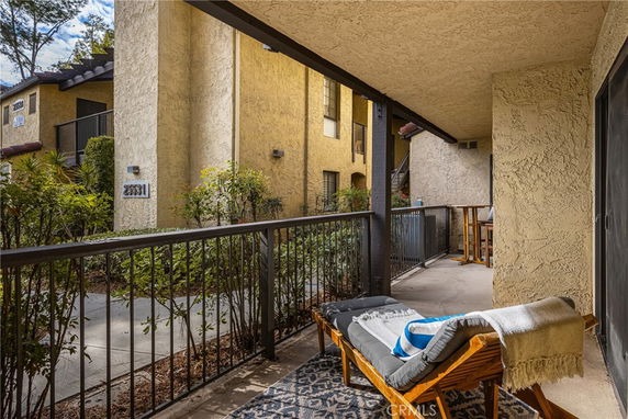 View from a covered outdoor patio facing a residential building exterior.
