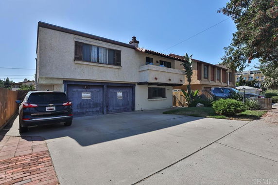 Front view of a two-story house with a double garage and a parking area in front.