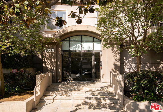Front view of a building entrance with an arched doorway and surrounding trees.