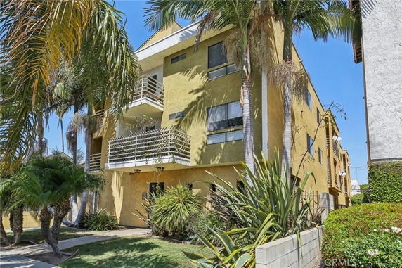 Front view of a multi-story building with balconies and a flat roof.