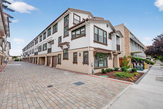 Front view of a multi-story residential building with a paved walkway.