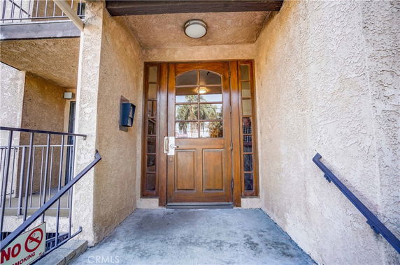 Entrance view with a wooden double door and surrounding stucco walls.