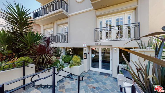 Front view of a multi-story building with balconies and a landscaped entrance.