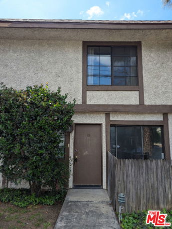 Front view of a two-story townhouse with a simple entrance and large windows.