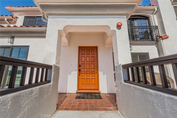 Front view of a house entrance with a wooden door and balcony railings.