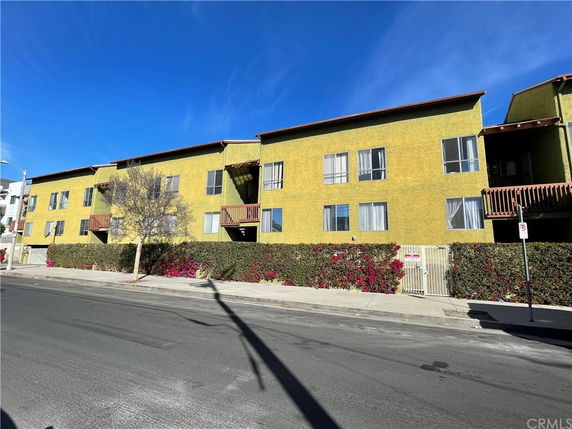 Front view of a multi-story residential building with yellow exterior and balconies.