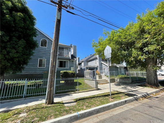 Front view of a two-story house with a fence and trees on either side.