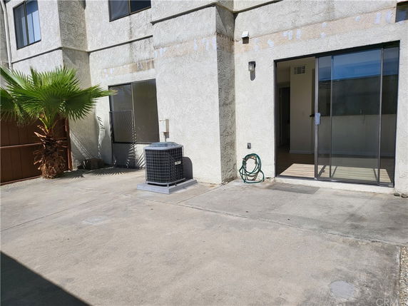 Exterior view of a building with sliding glass doors and air conditioning unit.