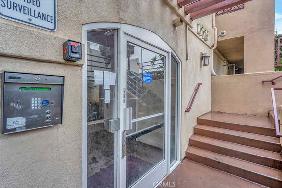 Entrance view of a building with a glass door and keypad entry system.