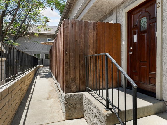 Front view of a residential building with a wooden door and fence.