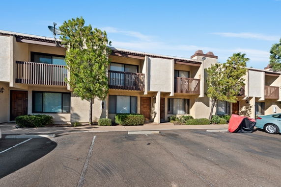 Front view of a two-story townhouse with balconies and a parking area in front.