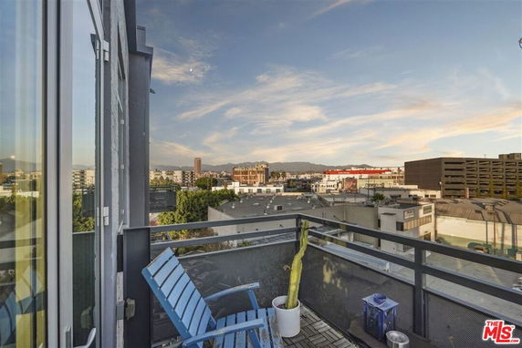 View from a balcony overlooking a cityscape with buildings and mountains in the distance.