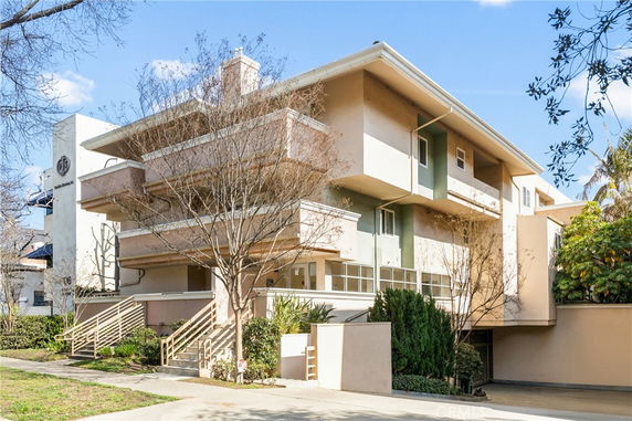 Front view of a multi-story residential building with balconies and stairs.