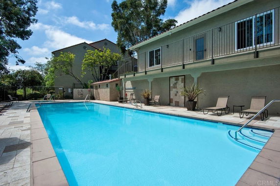 Outdoor swimming pool area with lounge chairs and surrounding building.