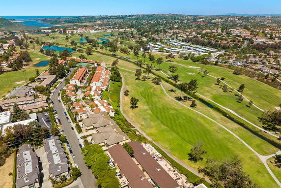 Aerial view of a residential area with green golf courses and a small body of water nearby.
