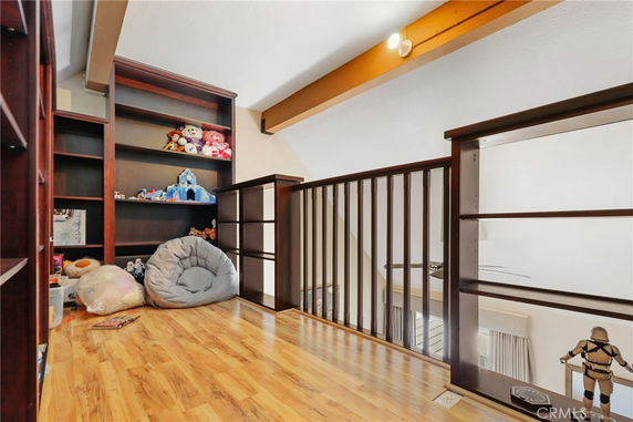 Indoor play area with wooden flooring, filled with toys and shelves.