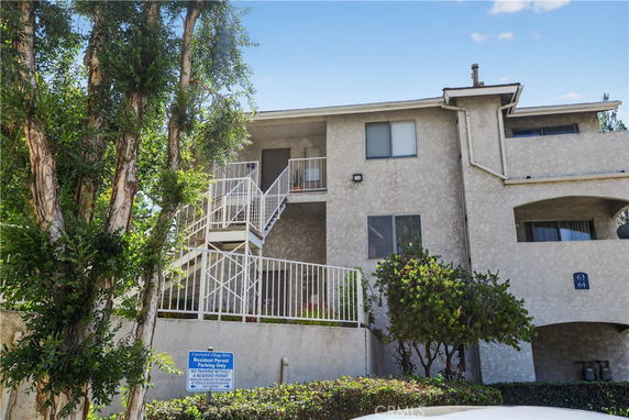 Front view of a multi-story residential building with exterior stairs and balconies.