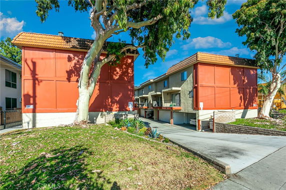 Front view of a two-story building with red and beige exterior and garage entries.