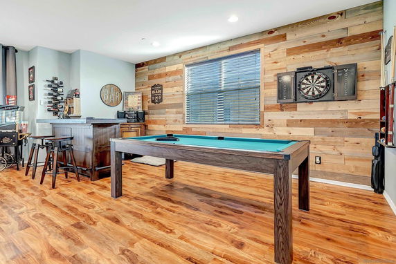 Recreational room with a pool table, dartboard, and bar area.