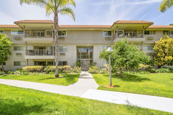 Front view of a multi-story residential building with balconies and a tiled roof.