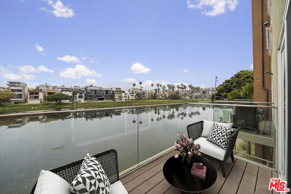 Balcony view overlooking a canal with modern houses in the background.