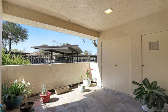 View of a covered parking area seen from an adjoining space with potted plants.