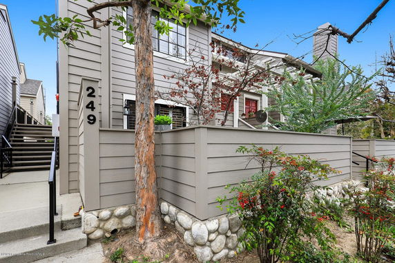 Front view of a house with a sloped roof and a fenced patio area.