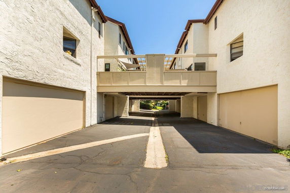 Outdoor parking area with garages underneath a residential building.