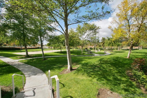 Outdoor park area with pathways, grassy fields, and scattered trees.